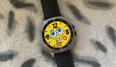The Samsung Galaxy Watch 8 Classic resting on a blanket showing a custom Facer watch face of Spongebob Squarepants.