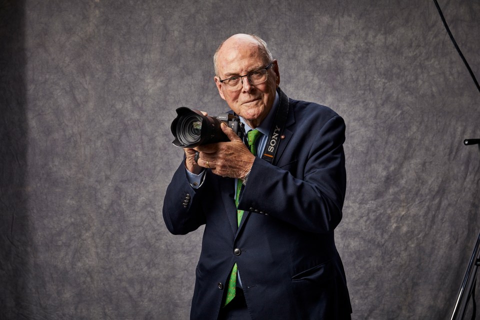 Portrait of Arthur Edwards holding a camera.