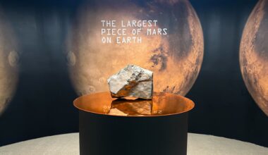 A large rock on a pedestal with a sign in the background that has a picture of Mars and says &quot;The Largest Piece of Mars On Earth.&quot;