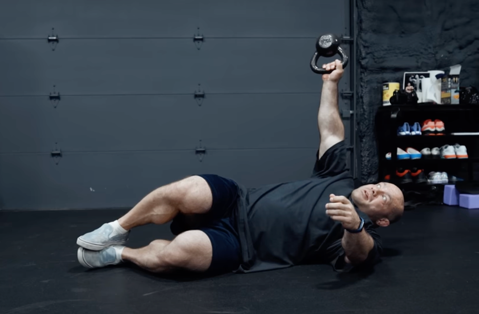 individual performing a kettlebell exercise on the floor