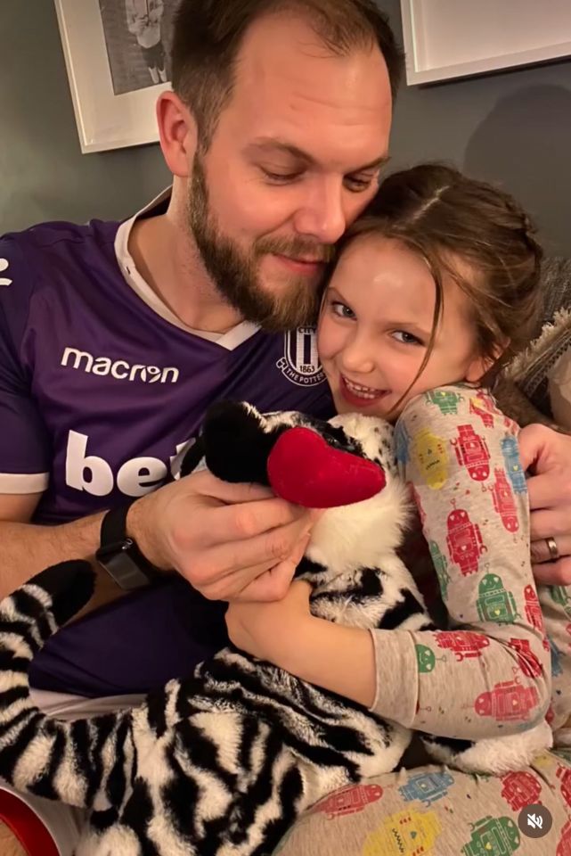 Father and daughter hugging a stuffed animal.
