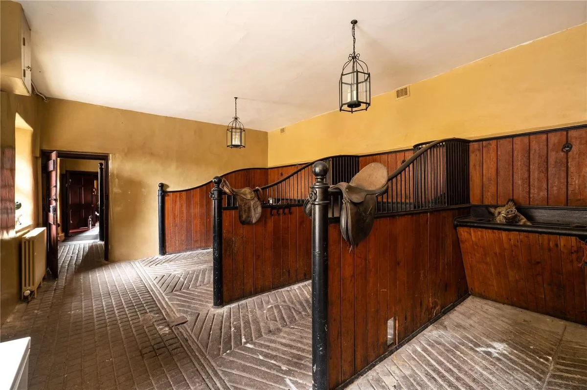 A set of stables with saddles perched on top of the wooden separators