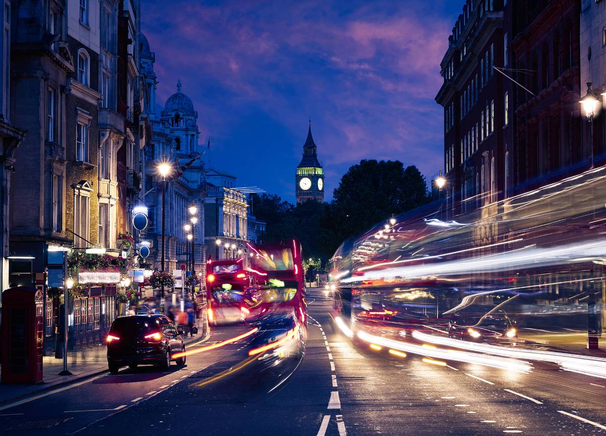 cars driving down a central london road with big ben in the back ground
