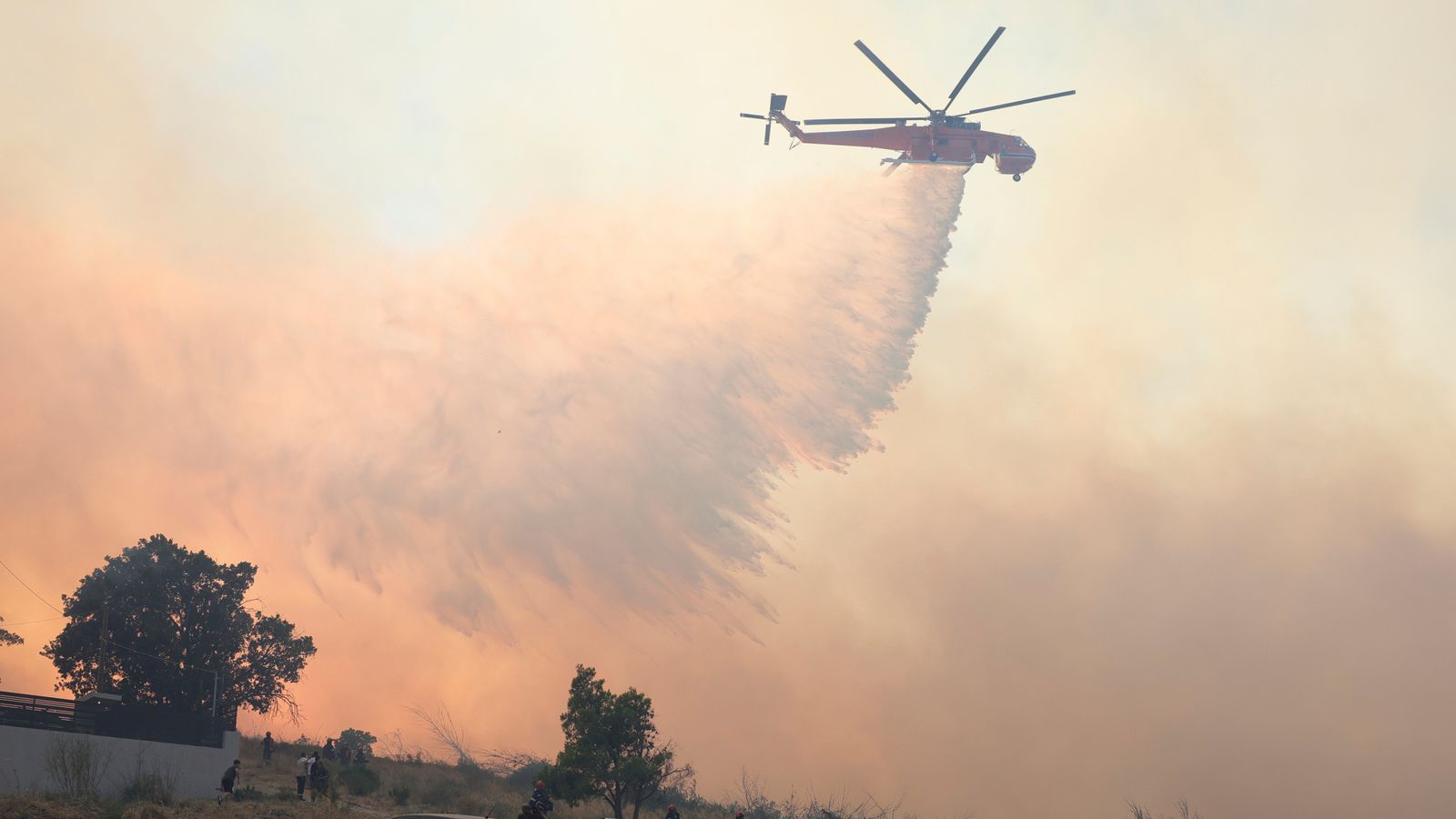 A helicopter drops water during a wildfire, in the northwestern suburb of Kryoneri, in Athens, Greece, Saturday, July 26, 2025. (AP Photo/Yorgos Karahalis)