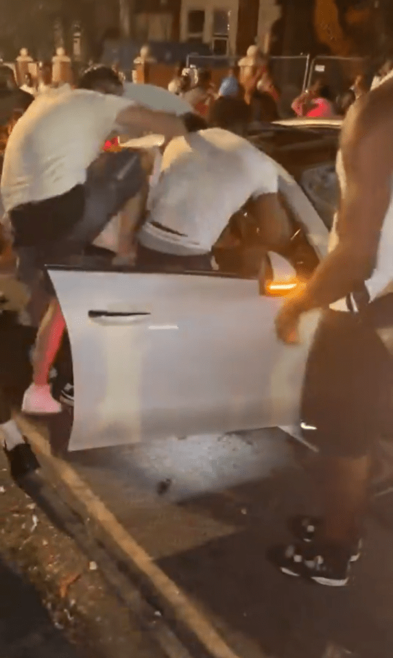 A gang surrounding a car, attacking the driver.
