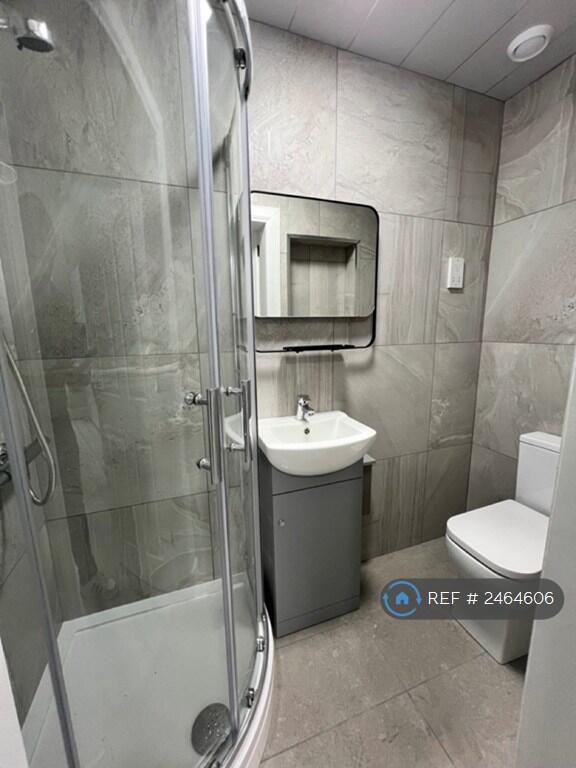 Studio flat bathroom with shower, sink, and toilet.