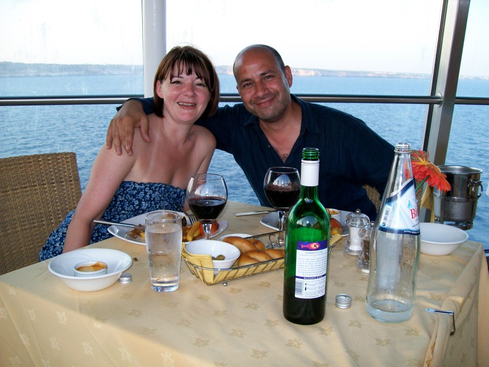 Couple enjoying a meal with wine and water overlooking the sea.