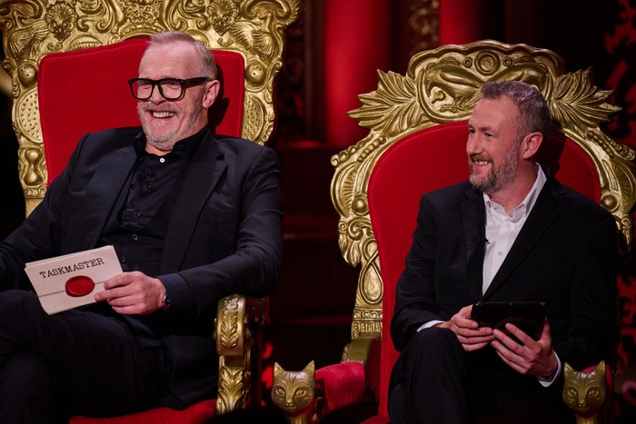 Greg Davies and Alex Horne sat down next to each other, smiling ahead.