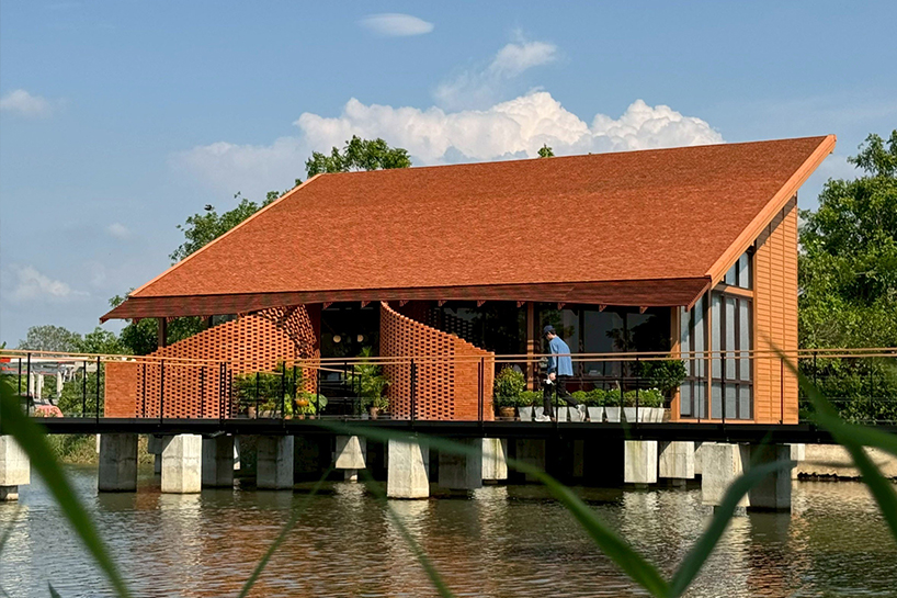 clad in terracotta tiles, morjor café floats above water pond in thailand