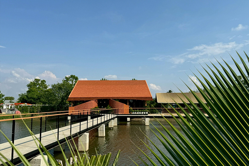 clad in terracotta tiles, morjor café floats above water pond in thailand