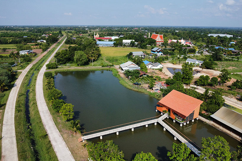 clad in terracotta tiles, morjor café floats above water pond in thailand