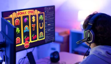 A man has headphones on as he watches an online poker machine game on a dual-monitor screen in a dimly lit room