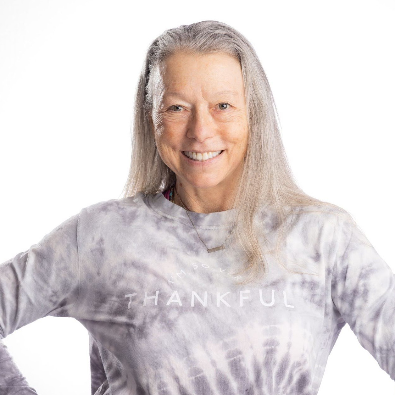 Head and shoulders of smiling women with her hands on her hips. She is wearing a sweatshirt with the word thankful across the chest 