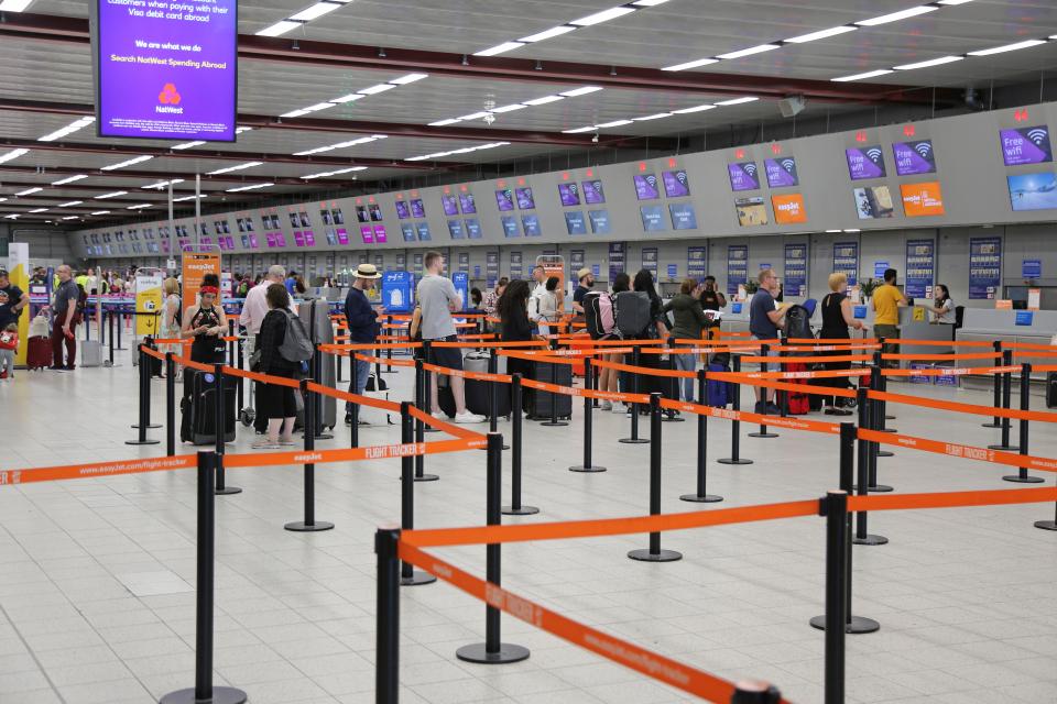 Passengers queuing at London Luton Airport check-in.