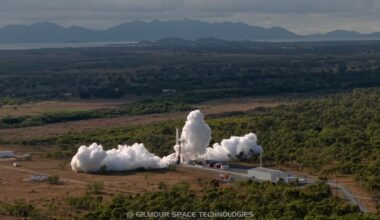 a white rocket launches into a cloudy sky, with mountains in the background