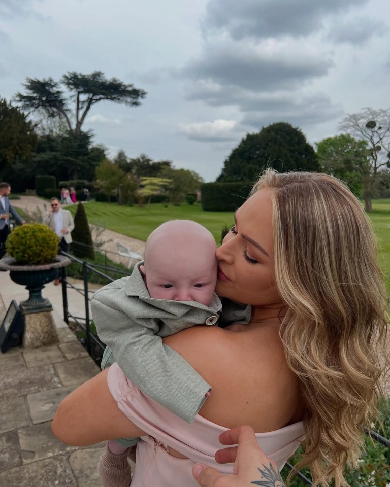 Woman holding baby on shoulder outdoors.
