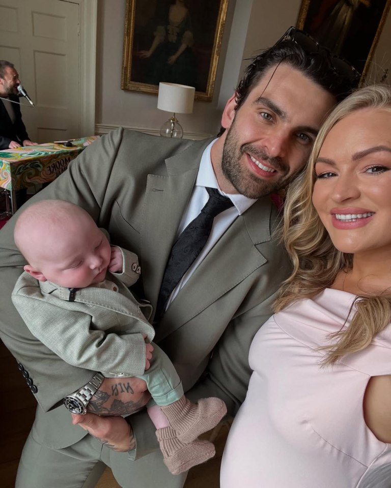 Family portrait: a man in a suit holds a baby, a pregnant woman stands beside them.