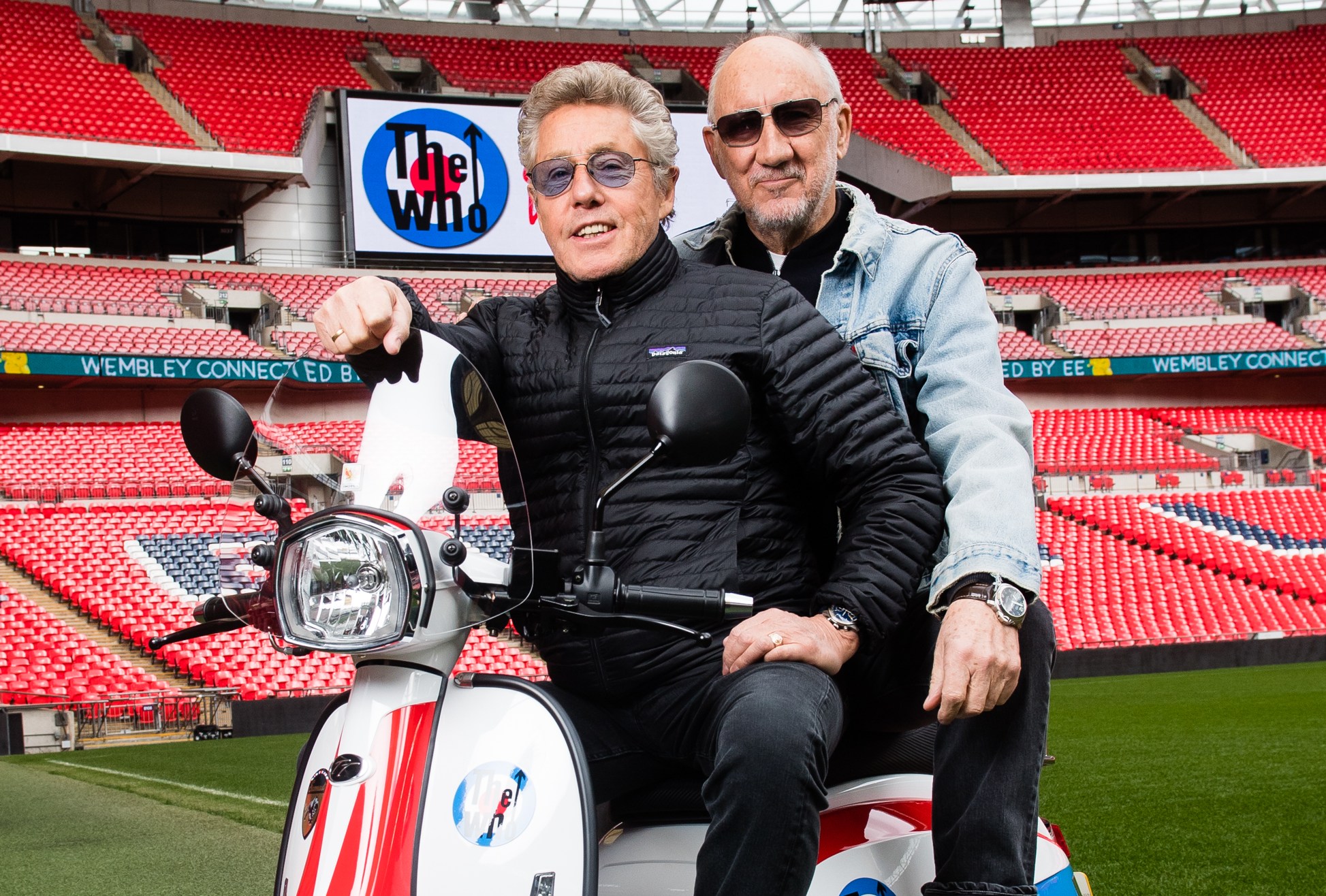 Roger Daltrey and Pete Townshend of The Who on a scooter in front of Wembley Stadium.