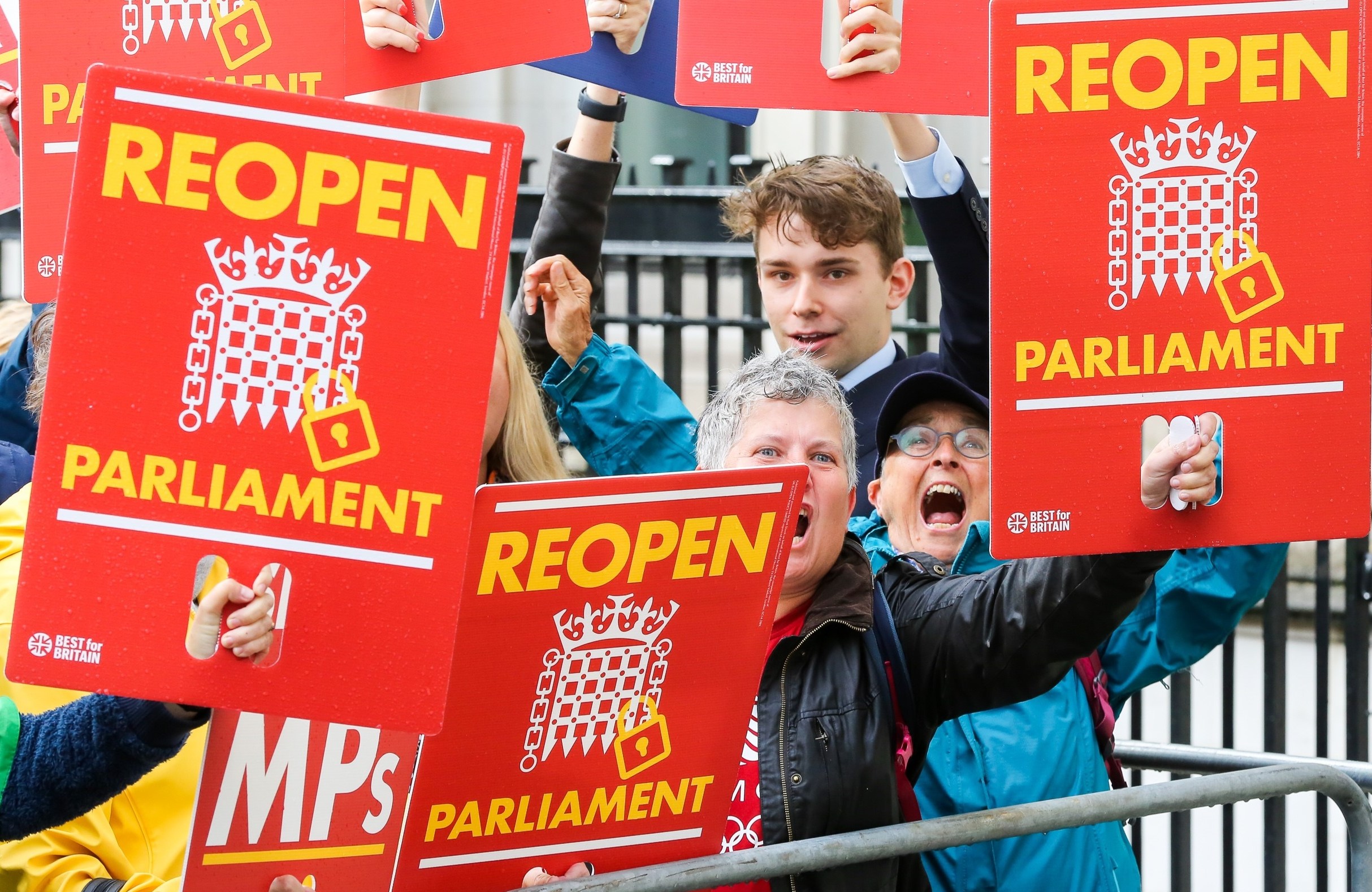 Protesters holding signs that say "Reopen Parliament" outside the Supreme Court.