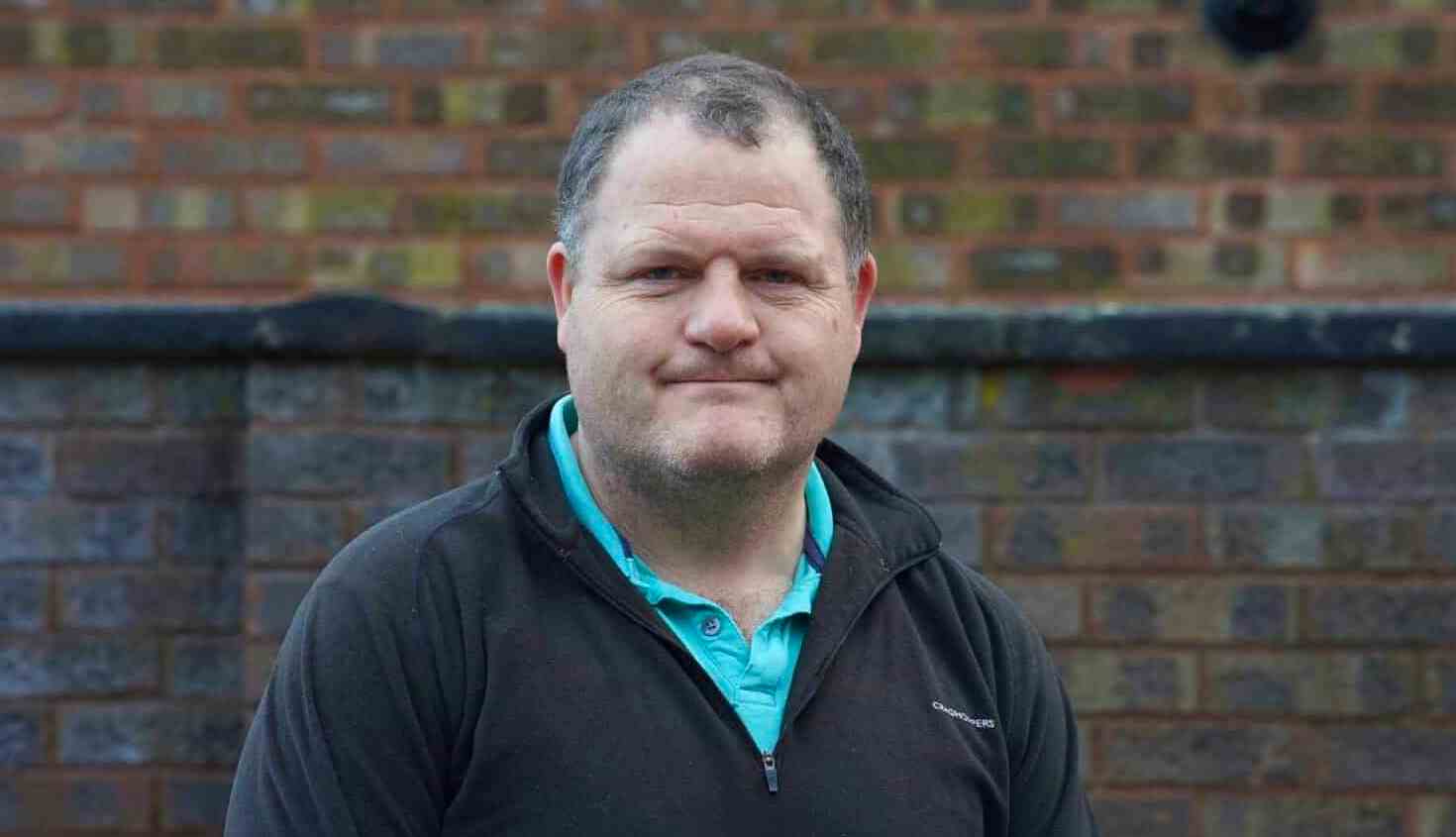 Portrait of a man in front of a brick wall.