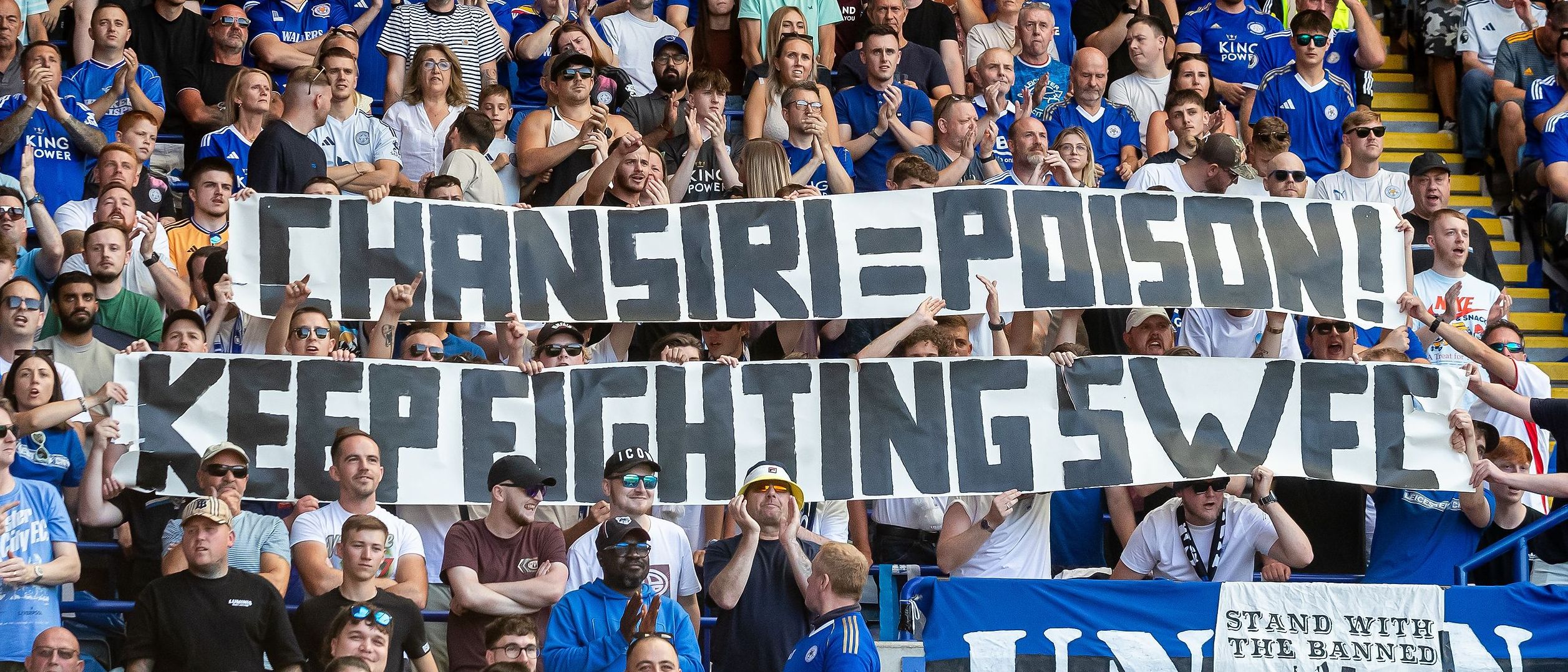 Leicester City fans holding a banner that reads "Chansari = Poison! Keep Fighting Swe".
