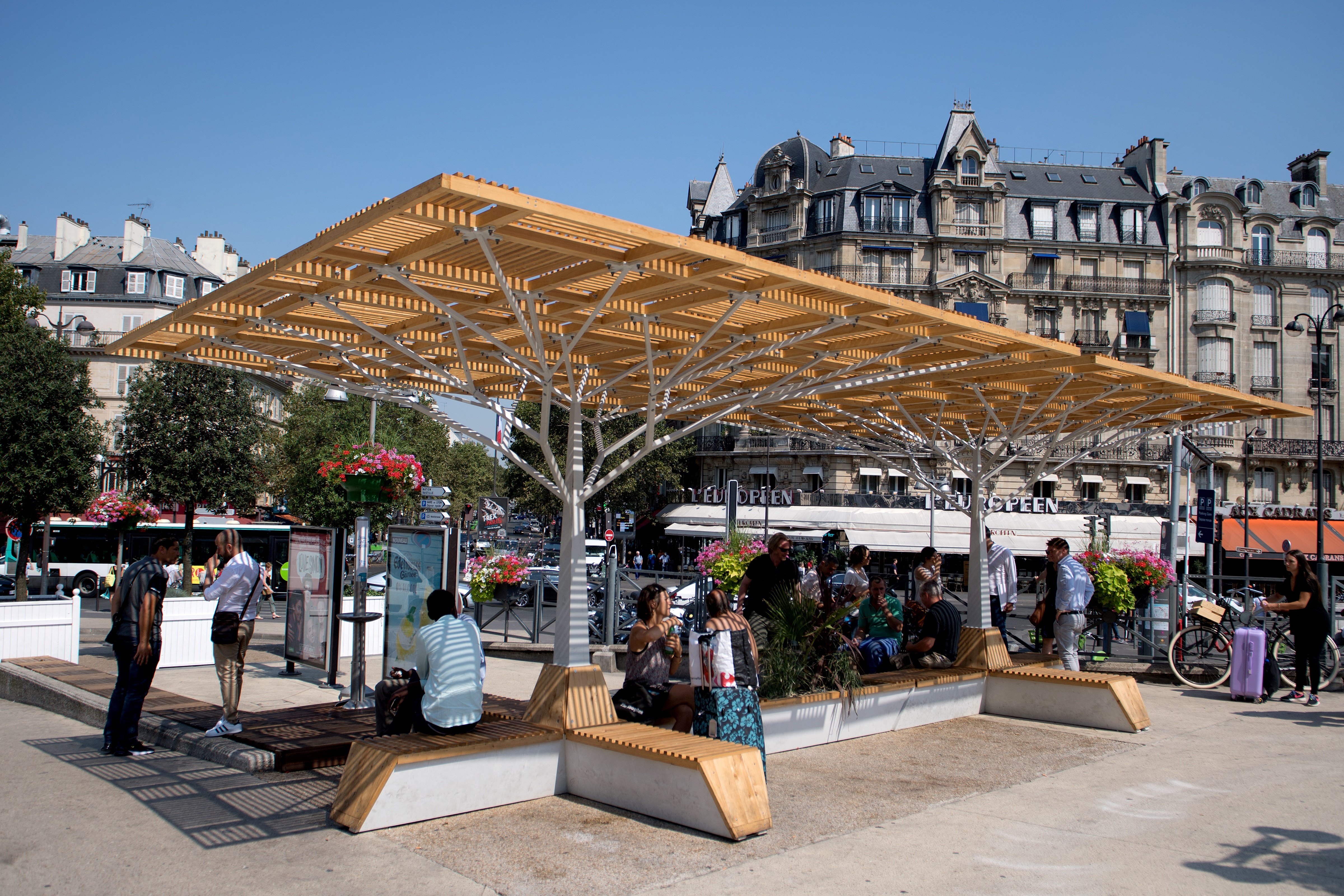 People sitting under a shaded structure in Paris.