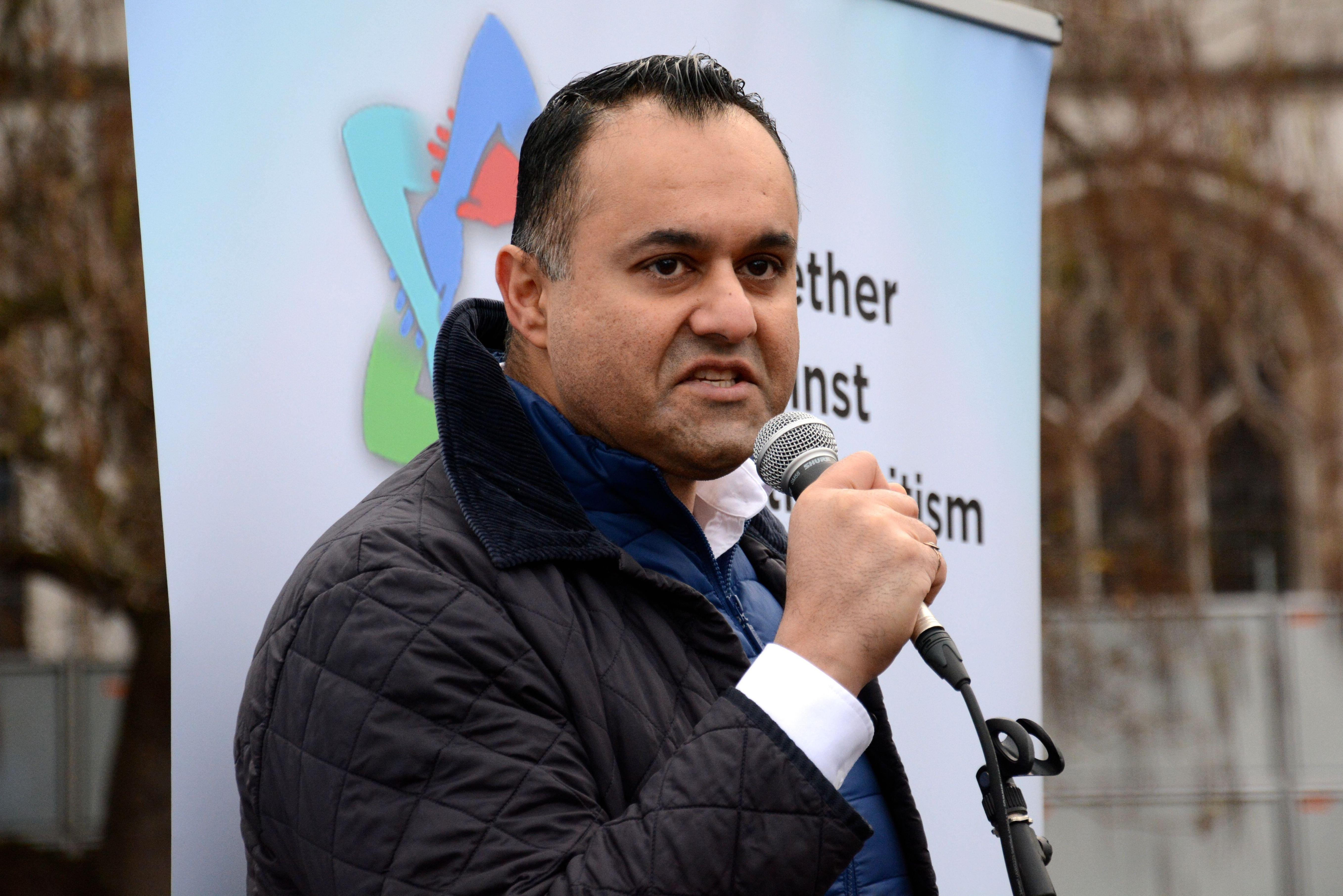 A man speaking at a demonstration against antisemitism in Parliament Square.