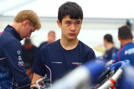 Young go-kart racer standing near his kart.
