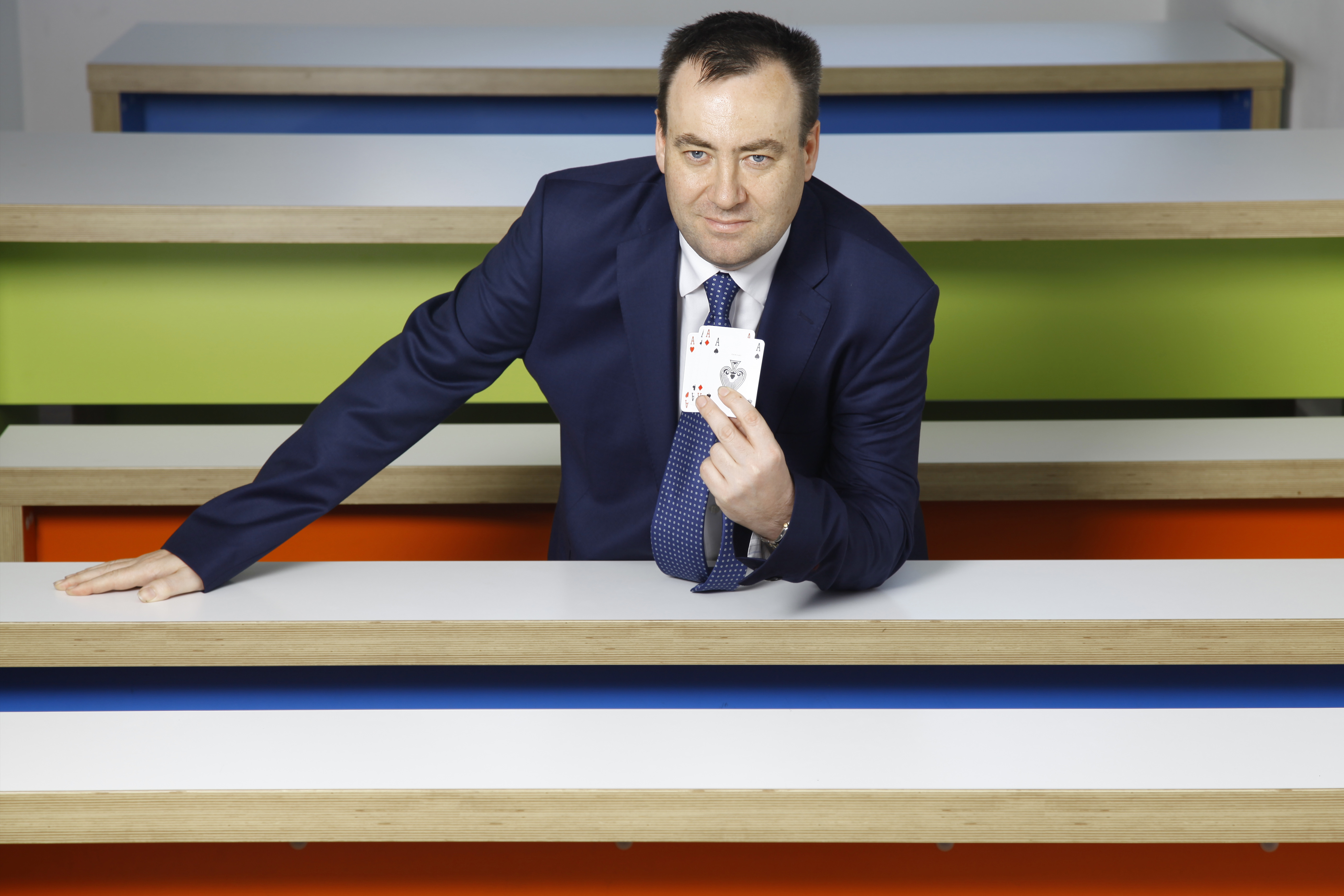 Portrait of Kenny Alexander, Chief Executive of GVC Holdings, holding playing cards.