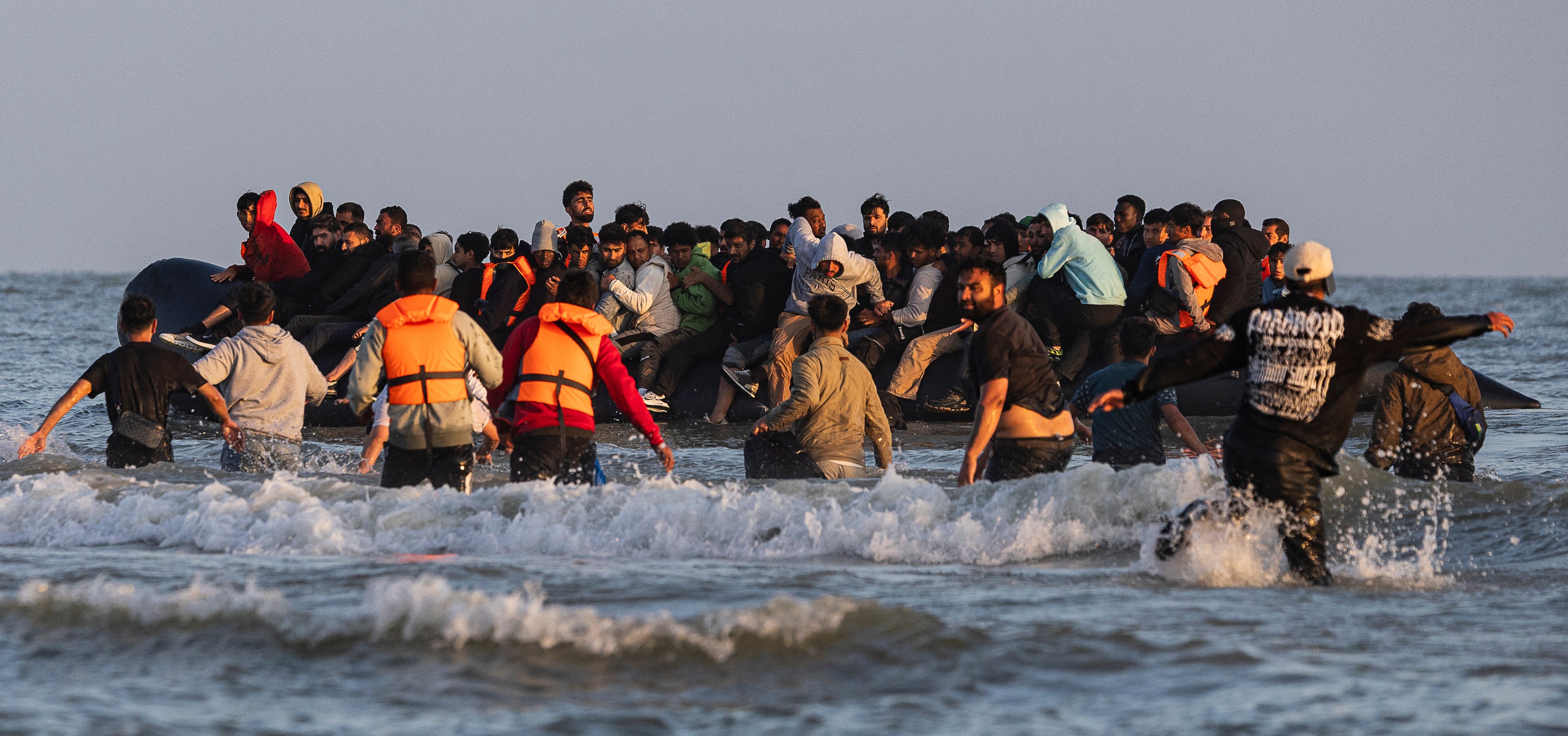 Migrants boarding a dinghy to cross the English Channel.