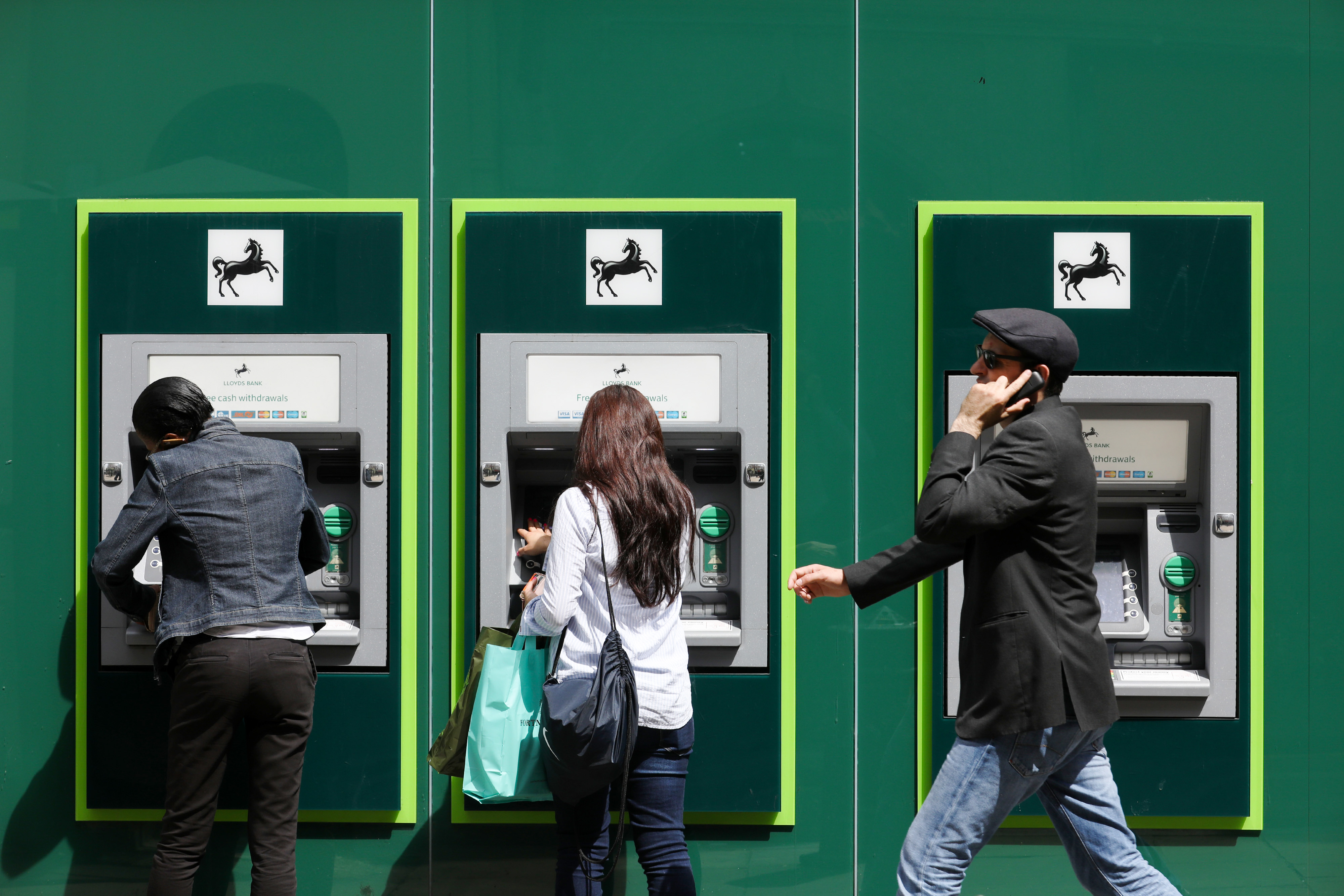 People using ATMs outside a Lloyds Bank branch in London.