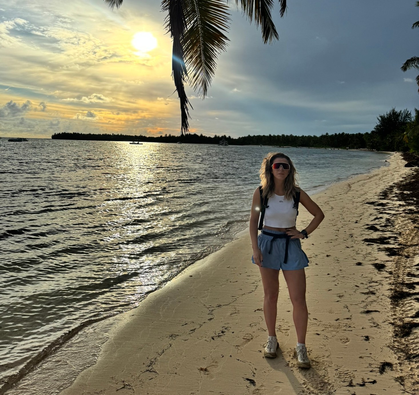 Woman standing on a beach at sunset.