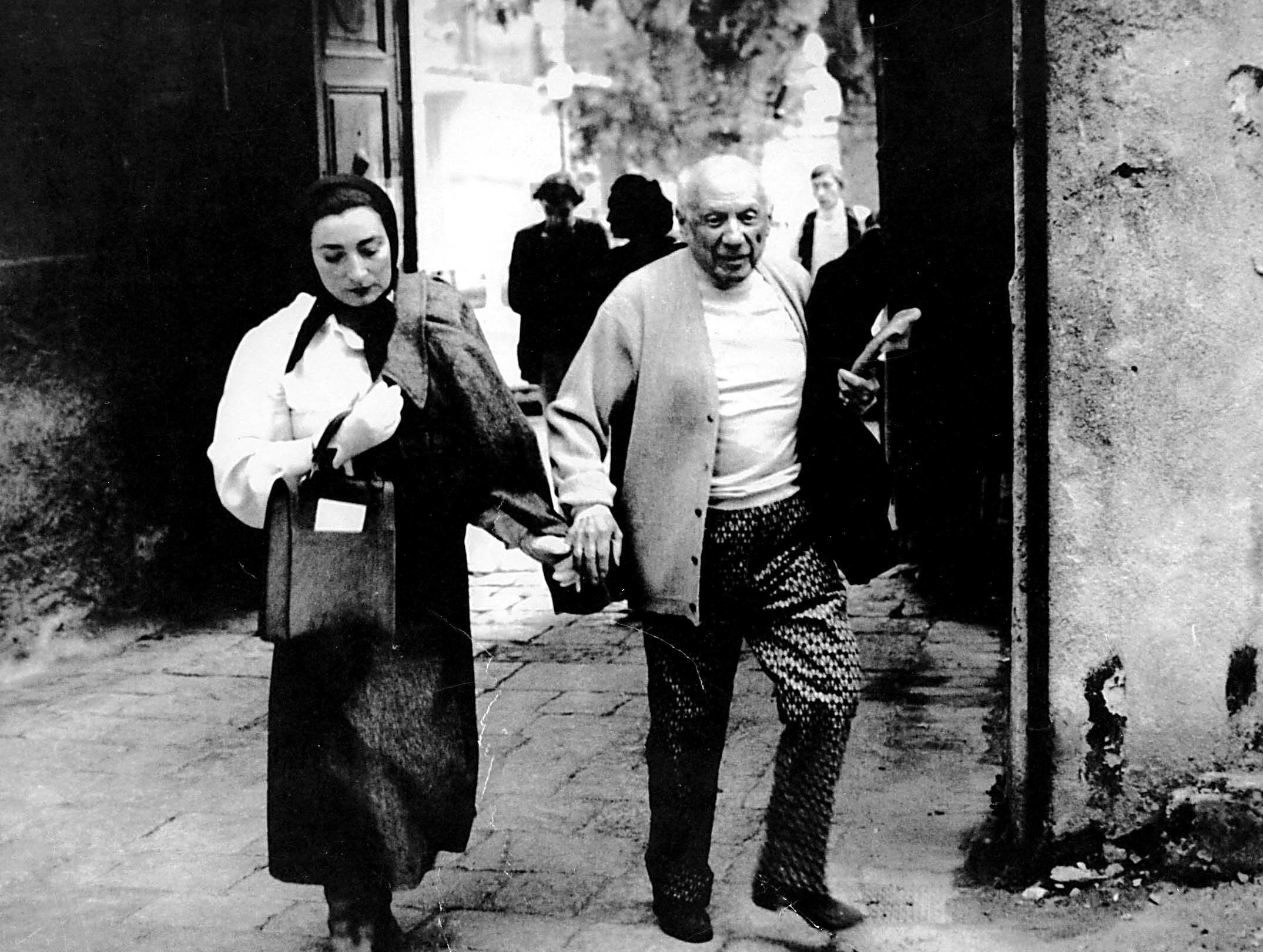 Pablo Picasso and Jacqueline Roque walking hand-in-hand.