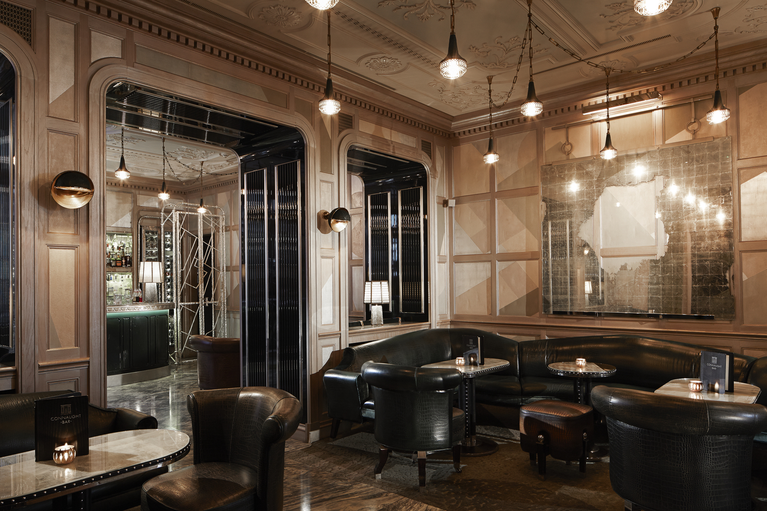 Connaught Bar interior with leather seating and ornate wood paneling.
