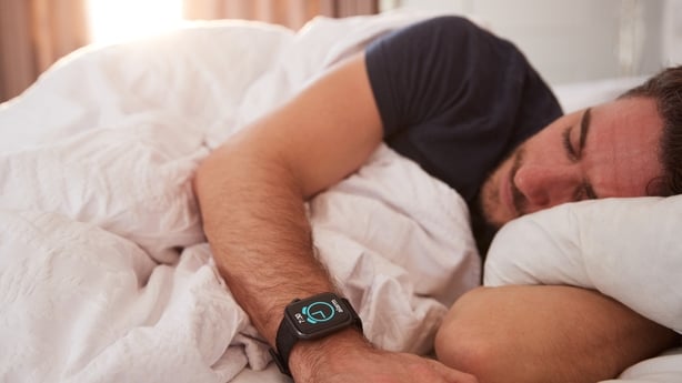 Man Asleep In Bed Wearing Smart Watch As Sun Breaks Through Curtains