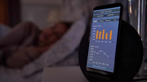 Woman Sleeping In Bed With Sleep Data App Running On Mobile Phone On Bedside