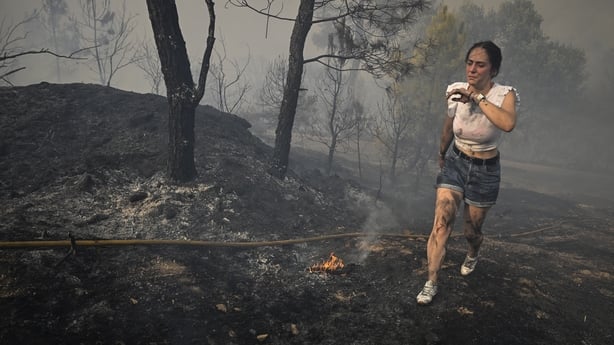 A woman tries to extinguish a wildfire near the village of Larouco