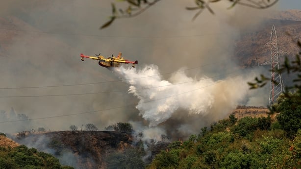 An Italian Canadair CL-415 aircraft drops liquid over a wildfire near the town of Delvine