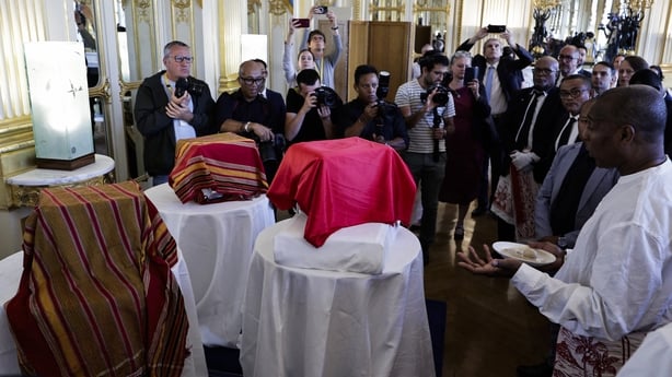A crowd gathered around three boxes covered by red clothes during a ceremony in which France returned three skulls to Madagascar. 