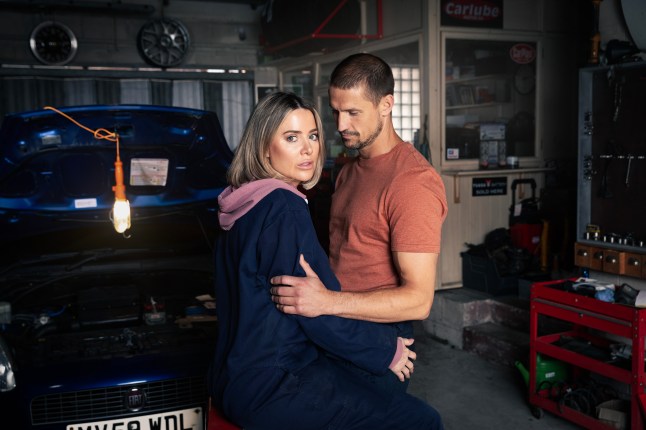 Abi and Carl hugging in the garage in Corrie