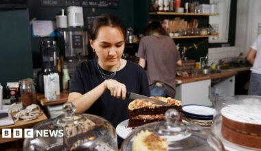 A young women cuts a cake in a cafe - stock shot