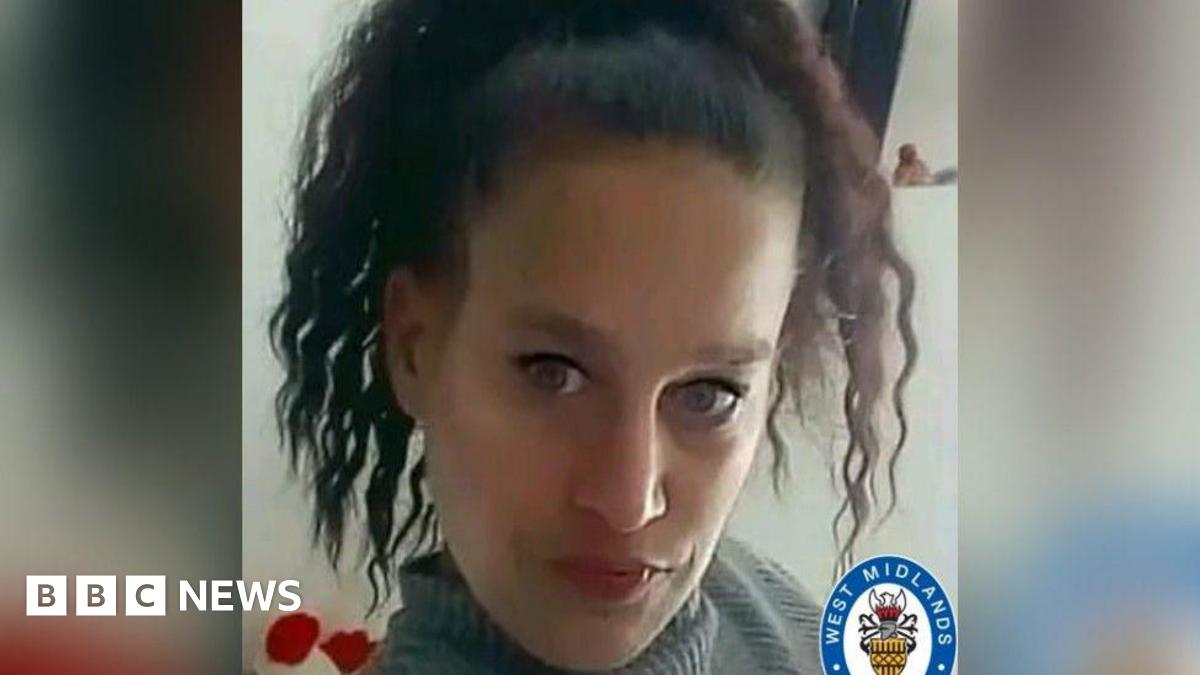 A woman with curly dark hair and black eyeliner, wearing a grey turtleneck, looks at the camera. The West Midlands Police logo is at the bottom right of the picture.
