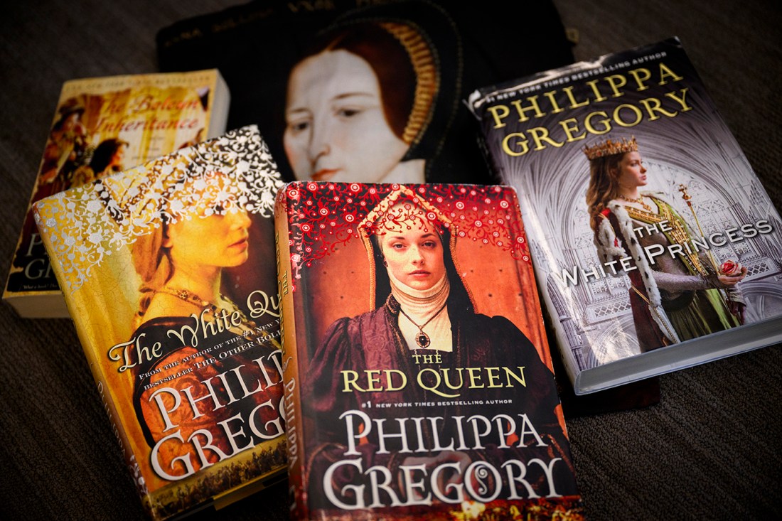 A collection of five Philippa Gregory historical fiction novels displayed on a dark surface. The books shown are 'The White Queen,' 'The Red Queen,' and 'The White Princess,' all part of The Cousins' War series. The book covers feature portraits of women in medieval and Tudor-era clothing and headdresses, with rich colors including gold, red, and purple. The author's name 'PHILIPPA GREGORY' is prominently displayed on each cover.