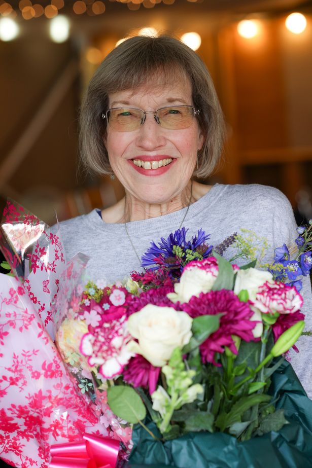 Karen with multiple bunches of flowers that were received.