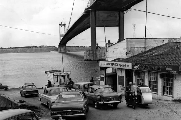 A black and white photo of cars waiting for a ferry