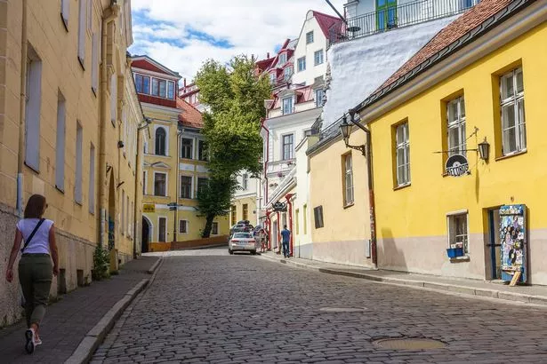 Woman walking by the Old town street during hot summer day is seen in Tallinn
