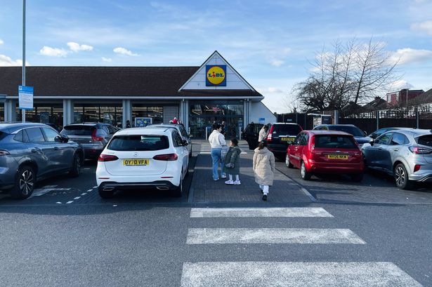 London, UK - March 02, 2025: A parking lot in front of Lidl supermarket with customers and vehicles under blue sky.