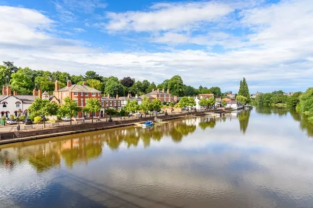 Residential buildings along a riverside street under blue sky with clouds on a summer day. Chester, England, UK.