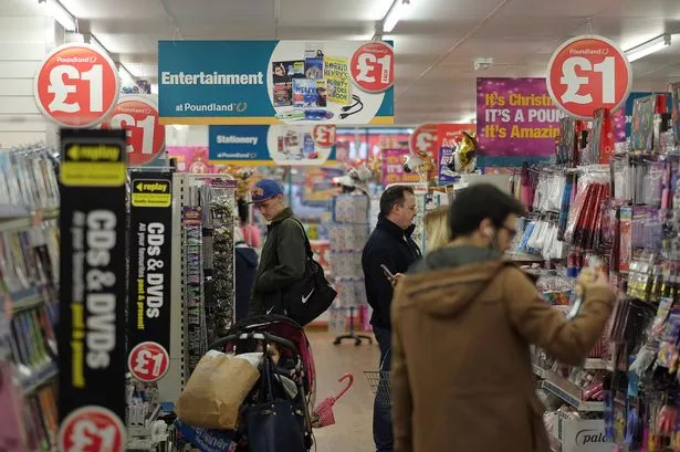 Customers browse products displayed for sale in the entertainment and stationery aisle inside a Poundland discount store,