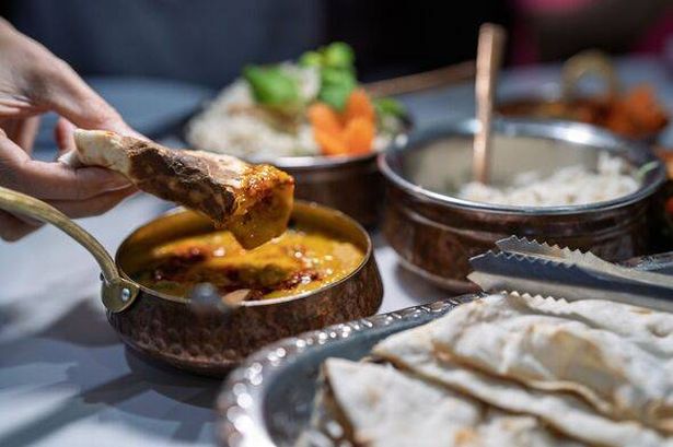 Hand Dipping Naan Bread into Indian Curry